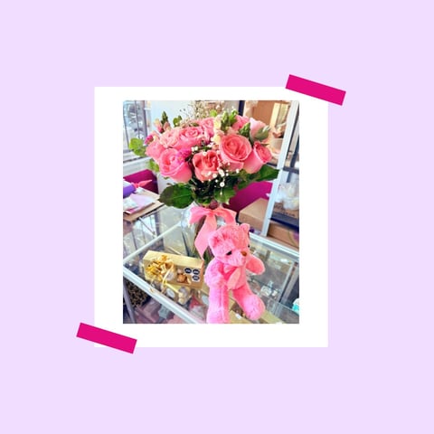 Polaroid-style photo of pink roses in a vase with pink ribbon, held by hot pink tape on lavender background