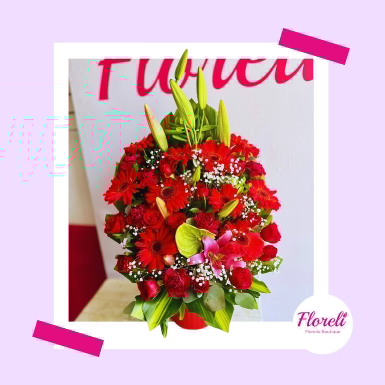 Oso de peluche color beige con lazo rosa que sostiene una caja de bombones negra en forma de corazón y un ramo de rosas rojas en el embalaje de regalo