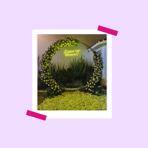 Polaroid-style photo of a circular living moss wall installation with neon yellow text, held with pink tape on purple background