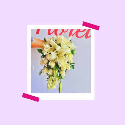 Polaroid-style photo of a yellow and white bridal bouquet with lilies and greenery, taped to a lavender background